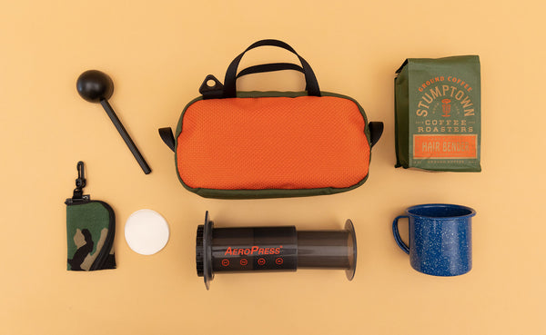 A Texturized Orange Grab Bag surrounded by travel coffee making items.